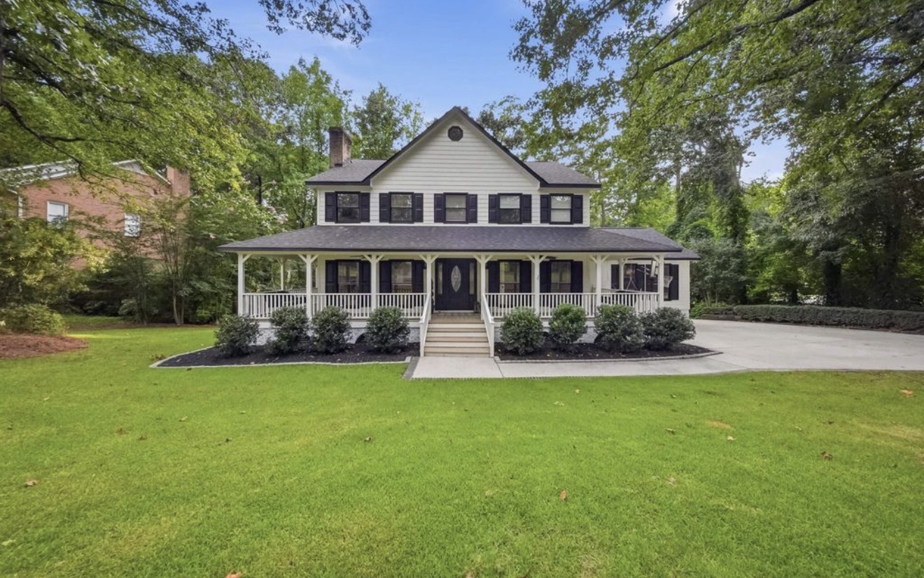White farmhouse with a wrap-around porch listed for sale near Lake Murray